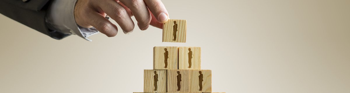 Businessman building a pyramid of wood blocks with people silhouettes